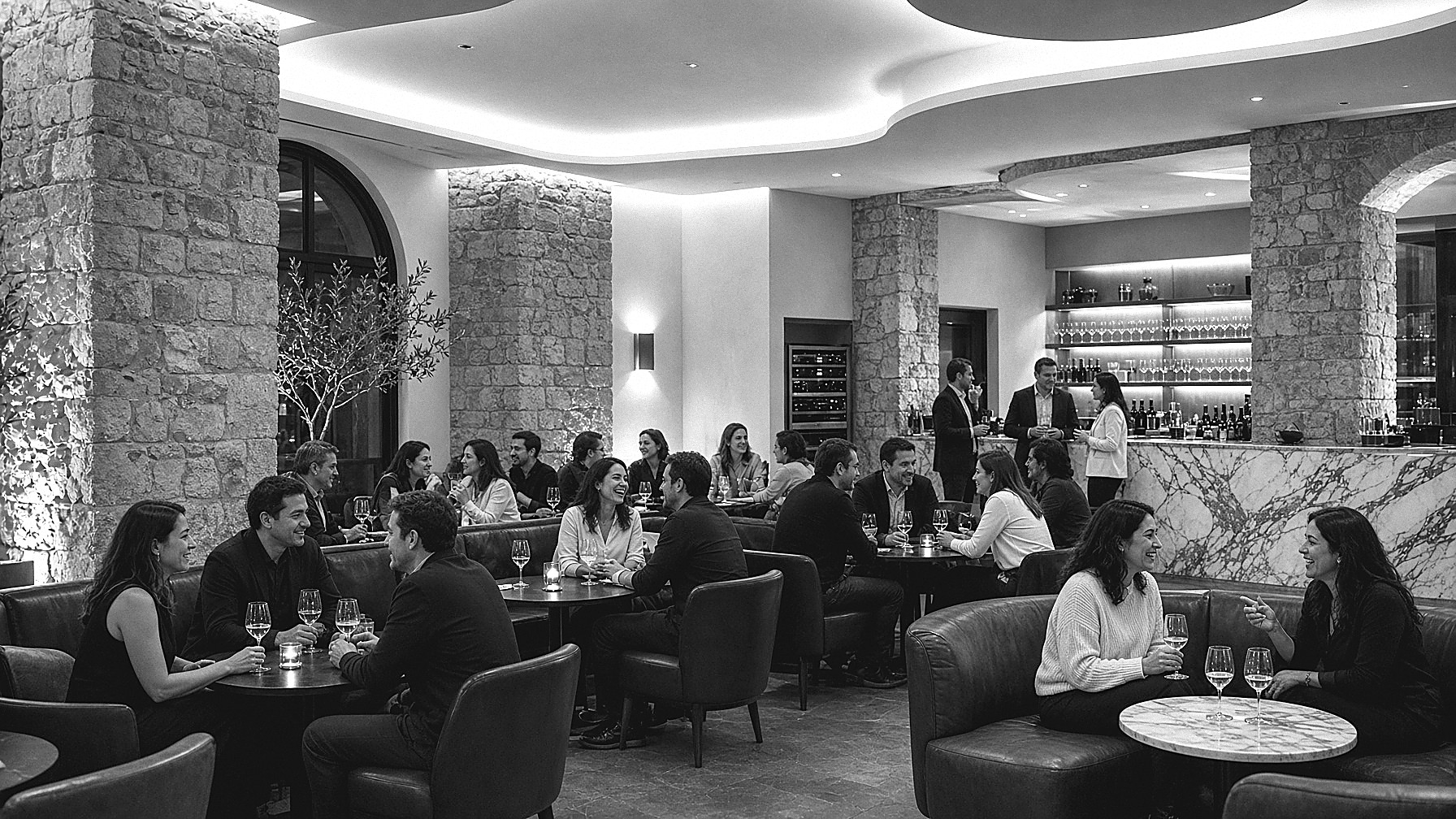 Lounge de hotel íntimo, unas veinticinco personas conversando