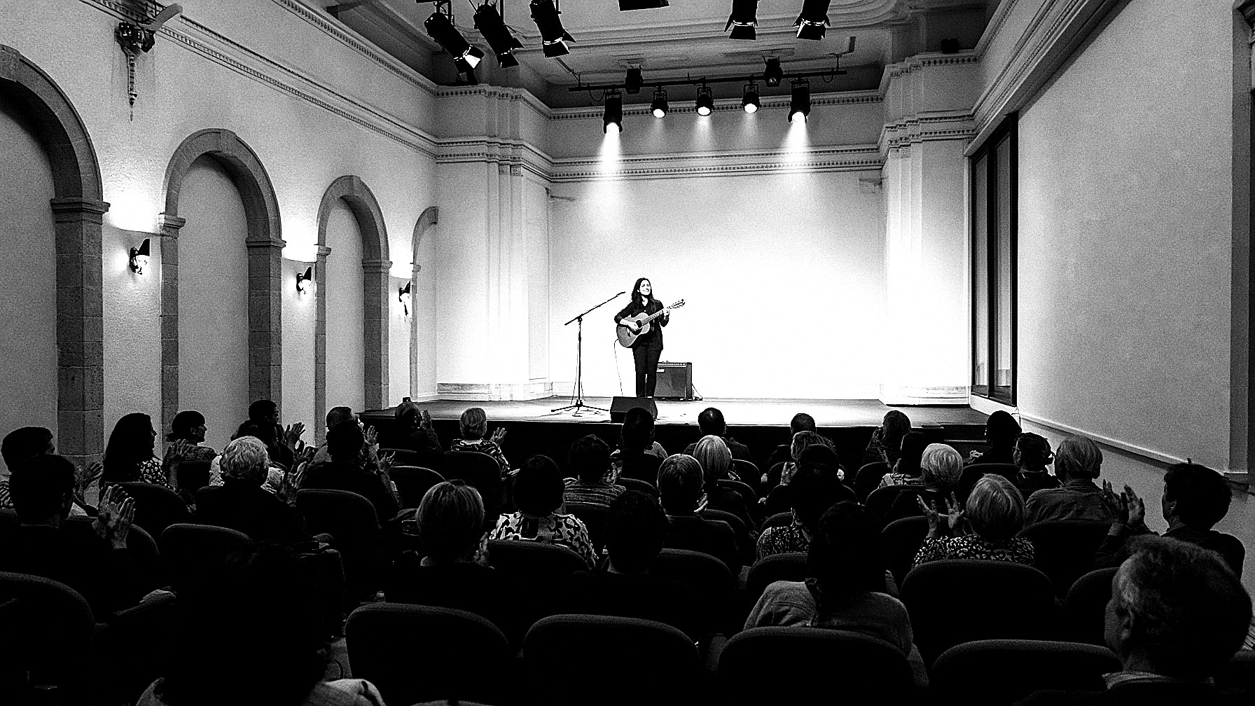 Concierto en una casa de cultura, el público lleno aplaude